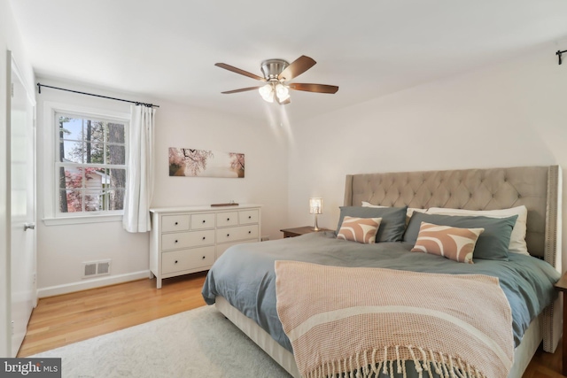 bedroom with light wood-type flooring, baseboards, visible vents, and ceiling fan