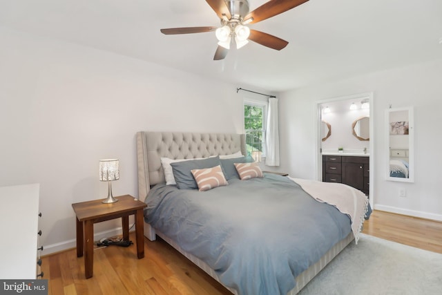 bedroom with connected bathroom, ceiling fan, baseboards, and light wood-style floors