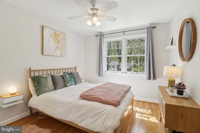 bedroom with baseboards, a ceiling fan, and light wood-type flooring