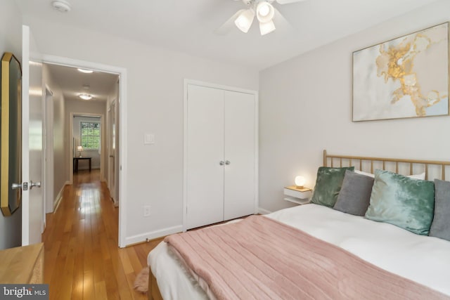 bedroom with wood-type flooring, baseboards, a ceiling fan, and a closet