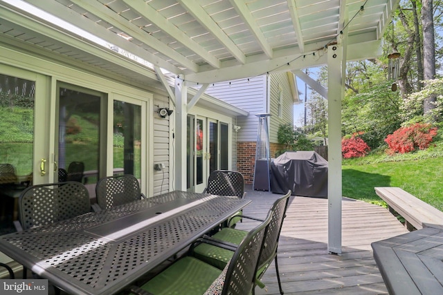 wooden terrace featuring a yard, outdoor dining space, and area for grilling