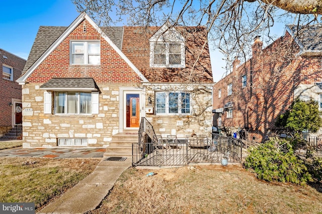 view of front of house with stone siding, roof with shingles, and a patio