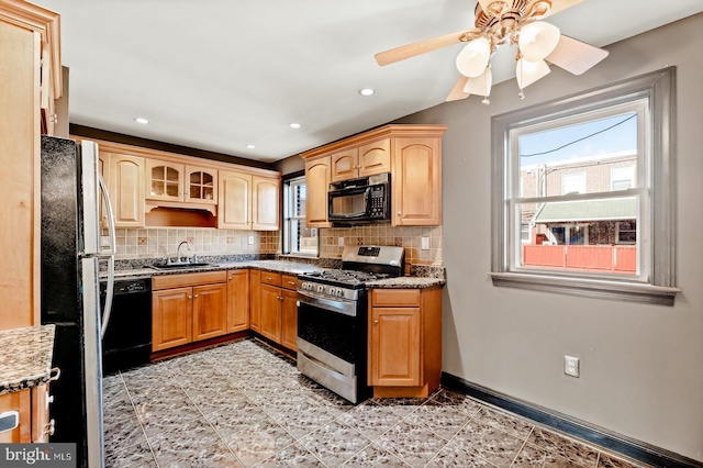 kitchen featuring a sink, decorative backsplash, baseboards, and black appliances