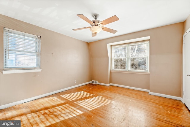 unfurnished room with baseboards, a healthy amount of sunlight, ceiling fan, and hardwood / wood-style flooring