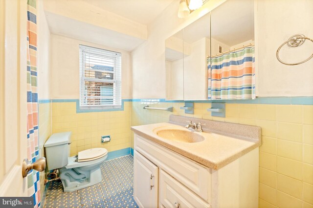 full bath with vanity, tile walls, toilet, and wainscoting