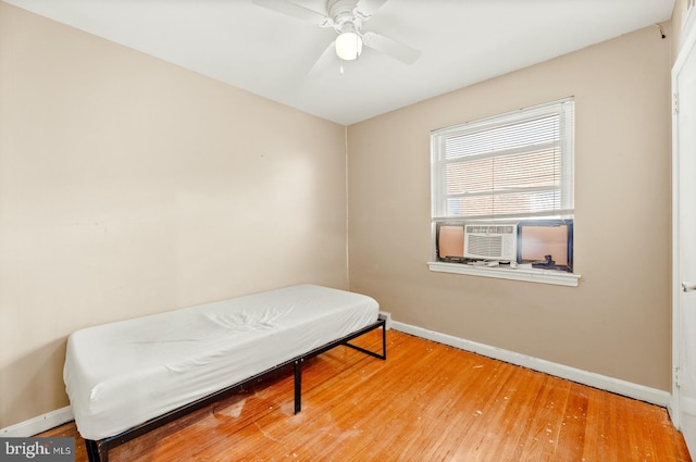 bedroom featuring ceiling fan, cooling unit, baseboards, and wood finished floors