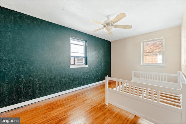 bedroom with a ceiling fan, baseboards, and wood-type flooring