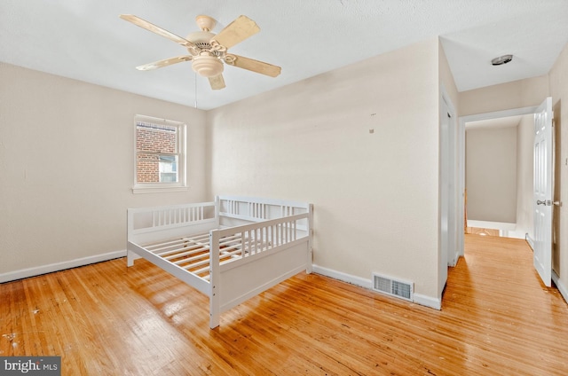 unfurnished bedroom with hardwood / wood-style floors, baseboards, visible vents, and a ceiling fan