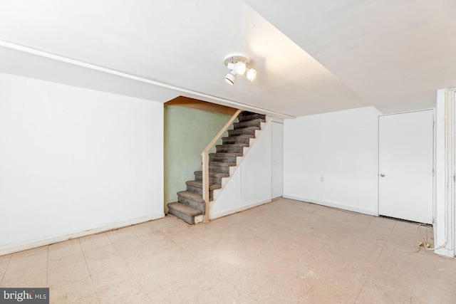 finished below grade area with stairs, tile patterned floors, and baseboards