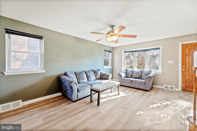 living area featuring light wood finished floors, visible vents, and baseboards