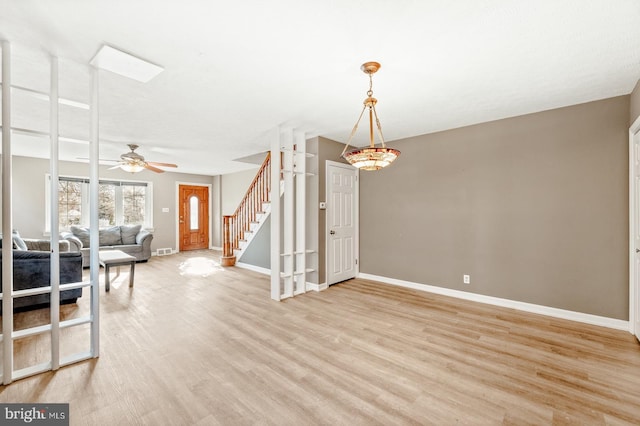 interior space with visible vents, baseboards, stairway, light wood-type flooring, and a ceiling fan