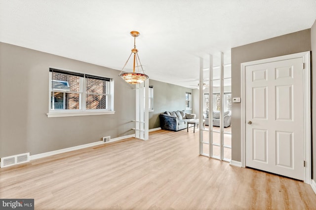 unfurnished dining area featuring visible vents, baseboards, and wood finished floors