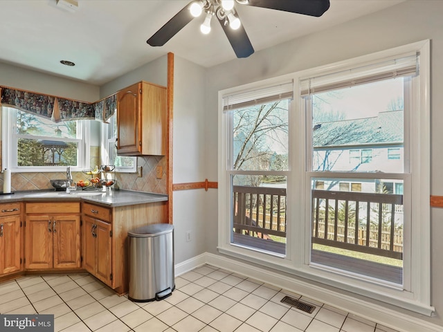 kitchen with light tile patterned floors, baseboards, visible vents, a sink, and tasteful backsplash