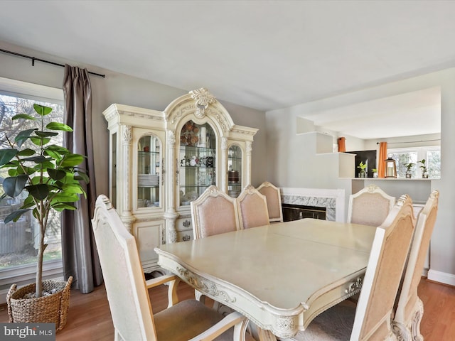 dining area featuring a high end fireplace, plenty of natural light, and wood finished floors