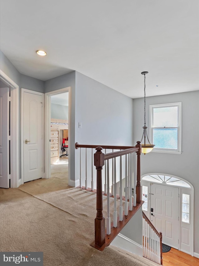 corridor with carpet flooring, an upstairs landing, and baseboards