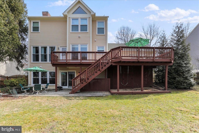 back of house featuring stairway, fence, a wooden deck, a chimney, and a lawn