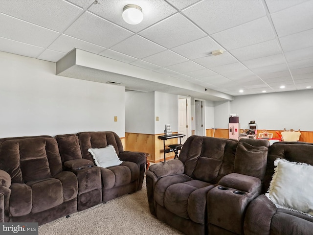 living area with wooden walls, carpet, a drop ceiling, and wainscoting