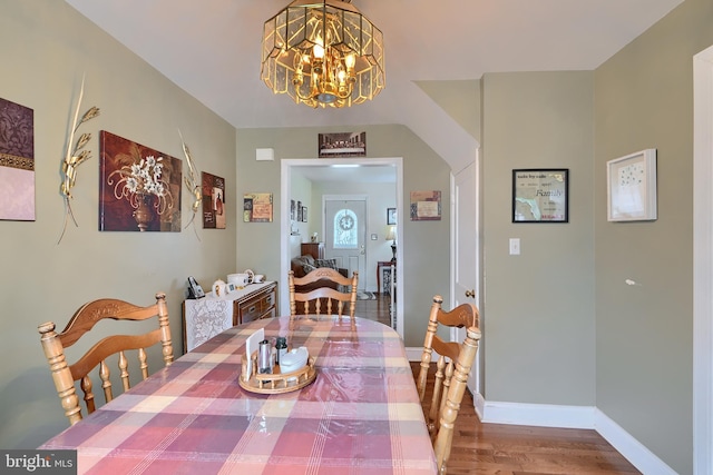 dining area featuring a chandelier, baseboards, arched walkways, and wood finished floors