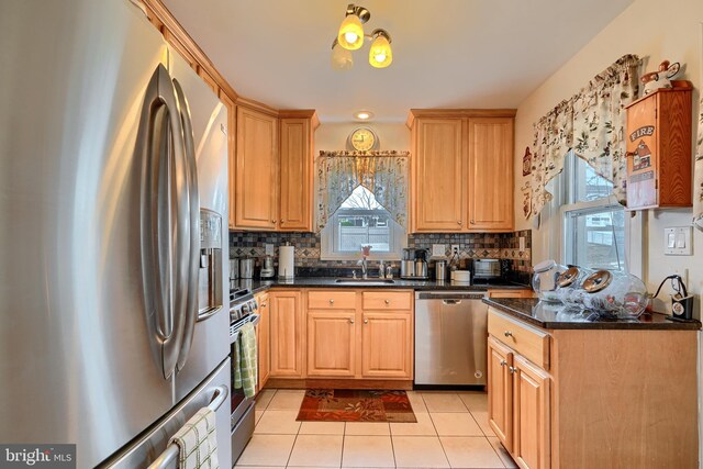 kitchen featuring light tile patterned floors, backsplash, appliances with stainless steel finishes, and a sink