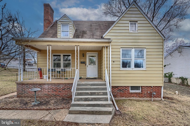 view of front of property featuring a shingled roof, a porch, and a chimney