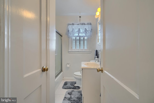 bathroom featuring baseboards, toilet, tile patterned floors, combined bath / shower with glass door, and vanity