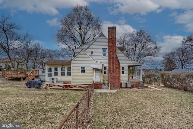 back of property featuring a wooden deck, a chimney, a yard, and fence