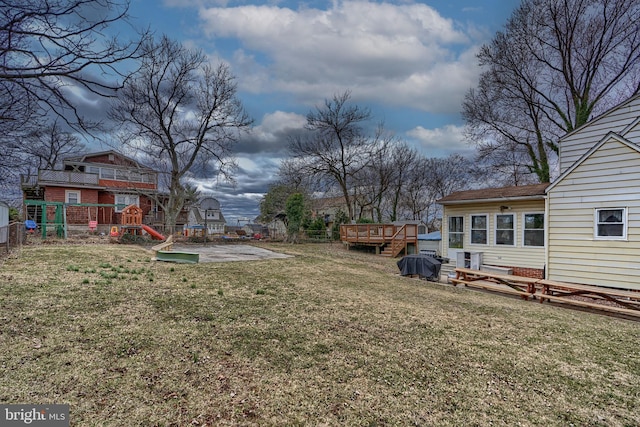 view of yard with a playground, a deck, and fence