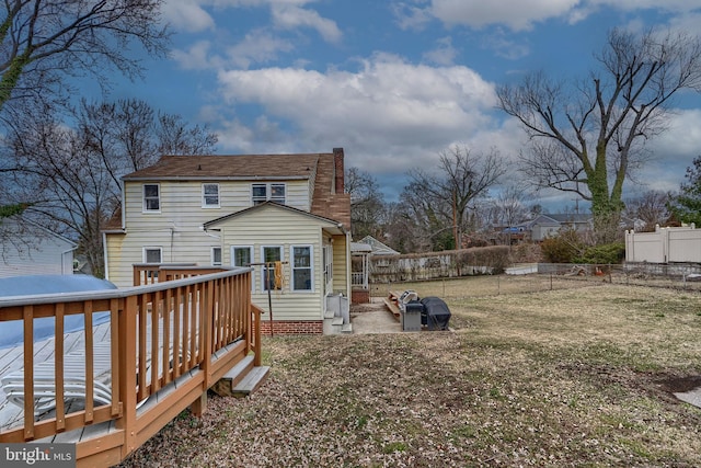 back of property with a yard, a deck, and a fenced backyard