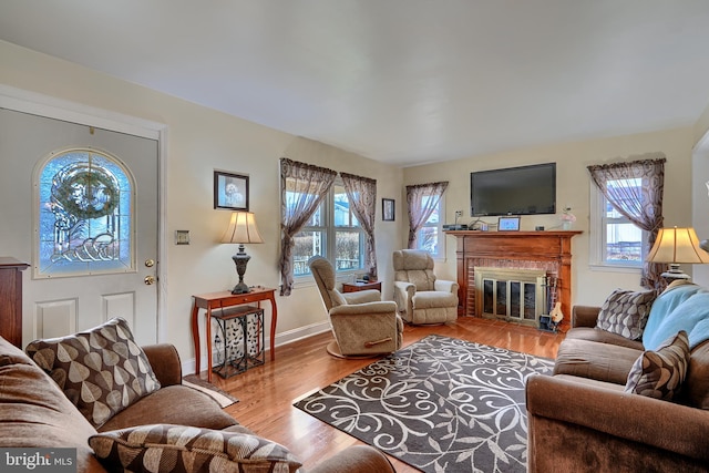 living area with a brick fireplace, baseboards, and wood finished floors