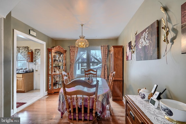 dining room with light wood-style flooring and an inviting chandelier