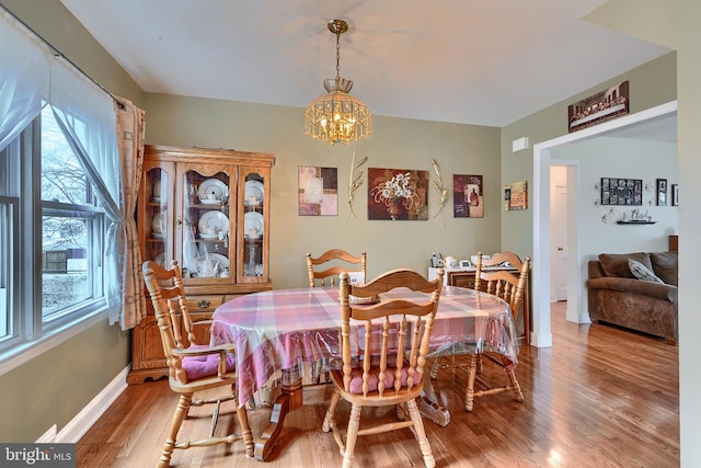 dining area featuring a notable chandelier, baseboards, and light wood finished floors