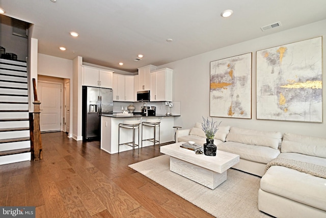 living area with dark wood-style floors, visible vents, recessed lighting, and stairway