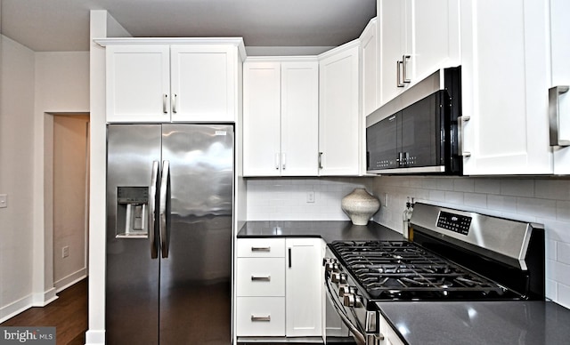 kitchen featuring stainless steel appliances, tasteful backsplash, dark countertops, and white cabinetry