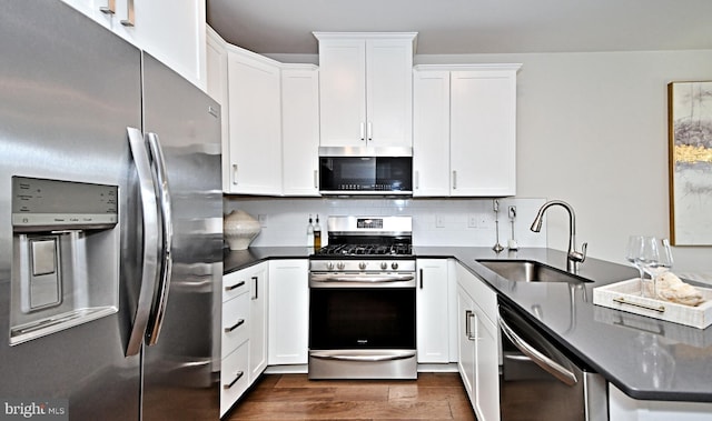 kitchen featuring a sink, dark wood-type flooring, white cabinets, appliances with stainless steel finishes, and tasteful backsplash