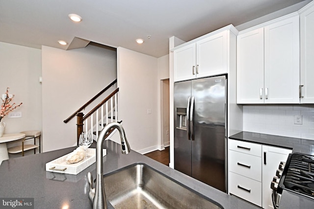 kitchen featuring dark countertops, decorative backsplash, appliances with stainless steel finishes, and white cabinetry