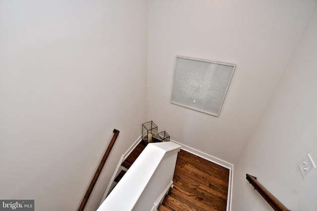 staircase featuring baseboards and wood finished floors