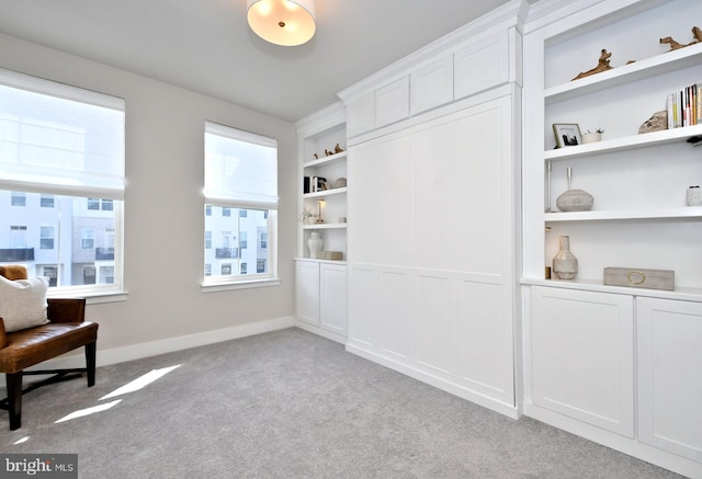 living area with carpet flooring, baseboards, and built in shelves