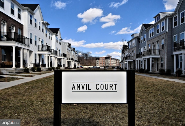 community sign featuring a residential view and a yard