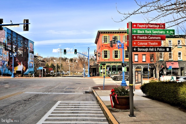 view of road with sidewalks, curbs, street lights, and traffic lights