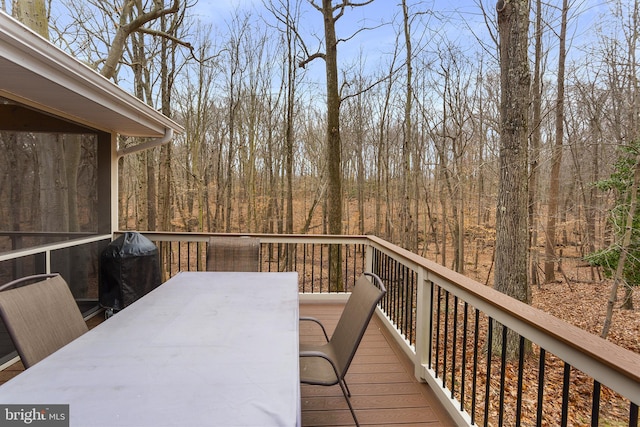 wooden deck featuring outdoor dining space and a view of trees