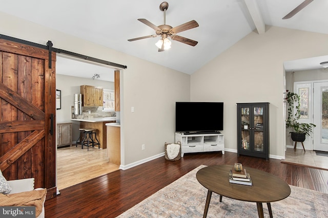 living area featuring ceiling fan, vaulted ceiling with beams, a barn door, and wood finished floors