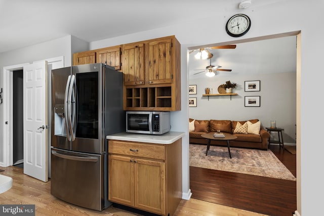 kitchen with brown cabinetry, a ceiling fan, light wood finished floors, light countertops, and appliances with stainless steel finishes