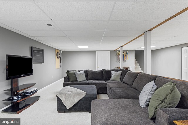 living room featuring stairway, carpet flooring, a paneled ceiling, and baseboards