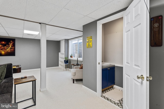 interior space with light carpet, a drop ceiling, and baseboards