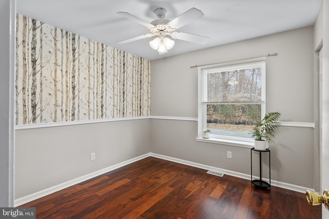 empty room featuring visible vents, wood finished floors, baseboards, and ceiling fan