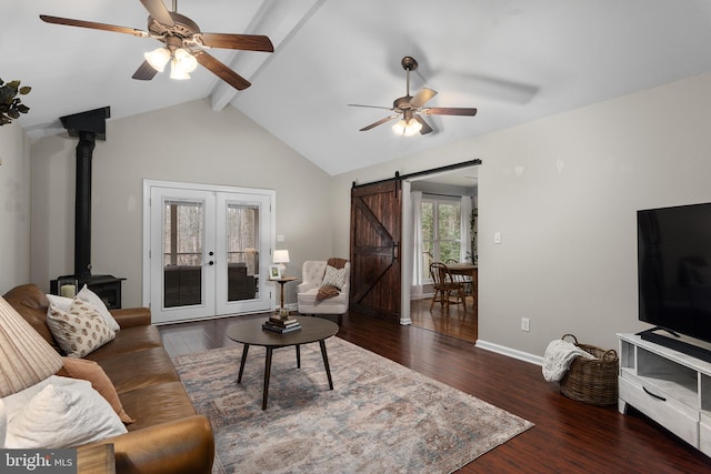 living room with a barn door, lofted ceiling with beams, wood finished floors, and ceiling fan