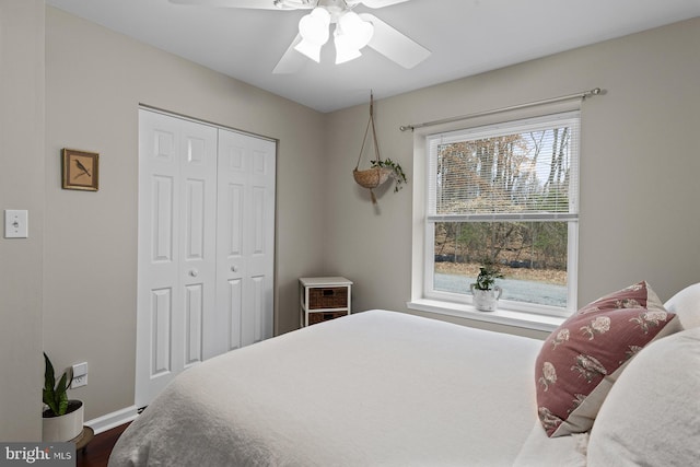 bedroom with dark wood finished floors, a ceiling fan, a closet, and baseboards