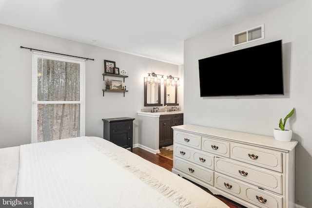 bedroom featuring visible vents, baseboards, ensuite bath, and dark wood-style floors