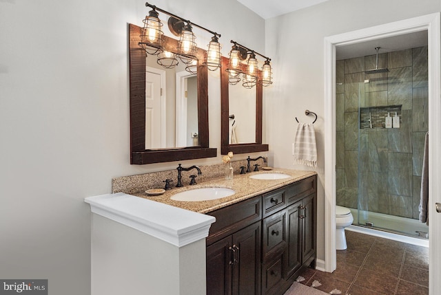 bathroom with a sink, toilet, double vanity, and a shower stall