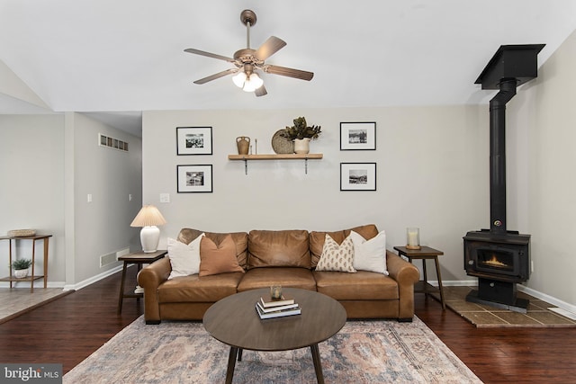 living area featuring a wood stove, wood finished floors, and visible vents